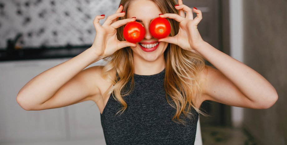 Девушка держит два помидора у лица