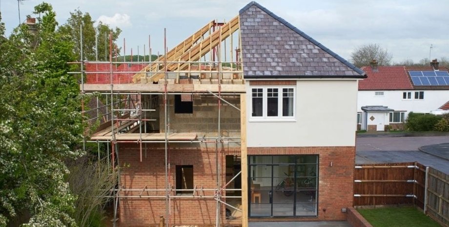 Новий приватний будинок на етапі будівництва з прибудовою у дворі