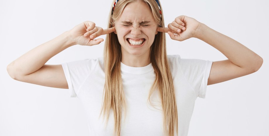 Девушка держит пальцы возле ушей