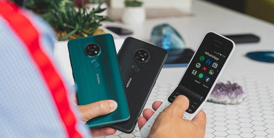 парень держит в руках телефон-раскладушку и смартфоны