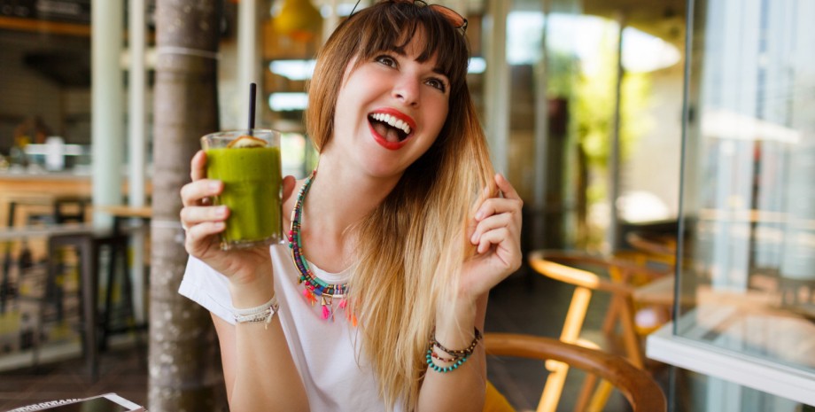 Девушка держит в руках стакан зеленого смузи Девушка держит в руках стакан зеленого смузи