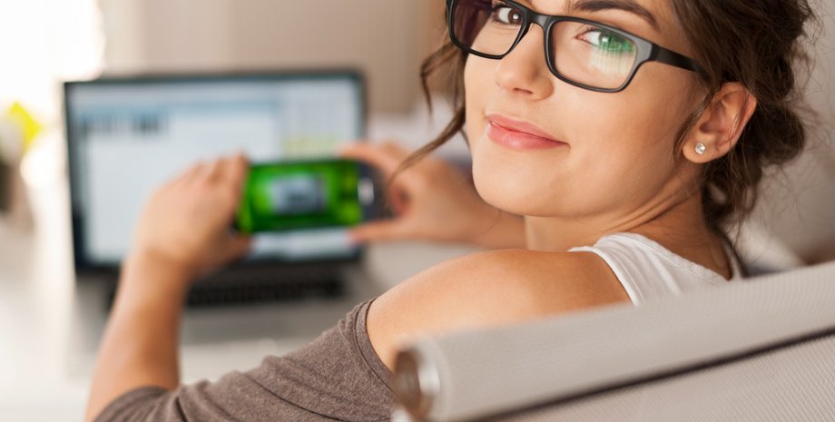 Девушка в очка держит смартфон