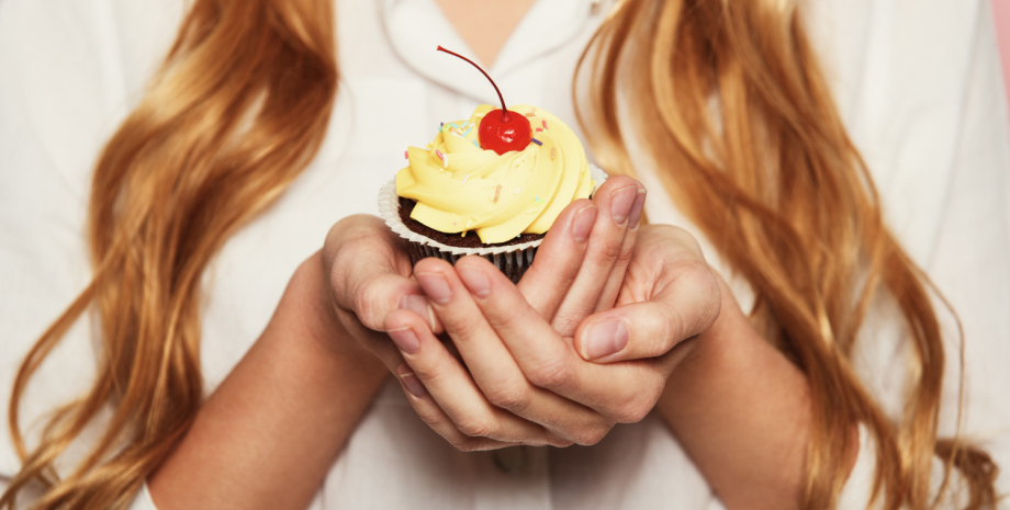 Девушка ест десерт Девушка держит в руках кекс