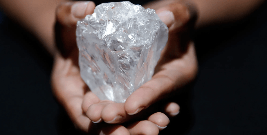Необроблений прозорий алмаз великого розміру в руках людини