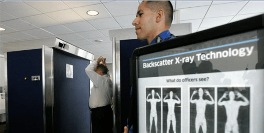 Сотрудник службы безопасности в аэропорту рядом со сканером тела, на экране показаны примеры изображений