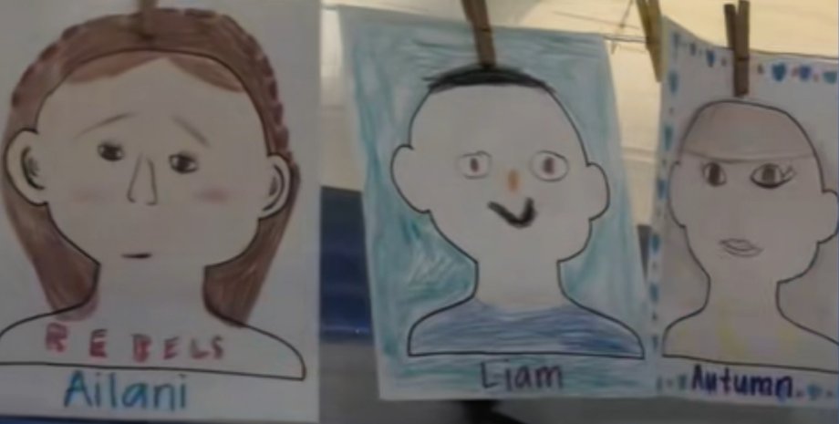 Рисунки детей, выполненные в классе, висят на веревке для выставки школьных работ