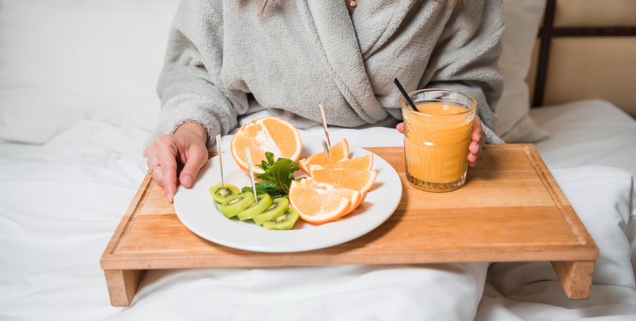 Дівчина тримає тацю із соком і фруктами