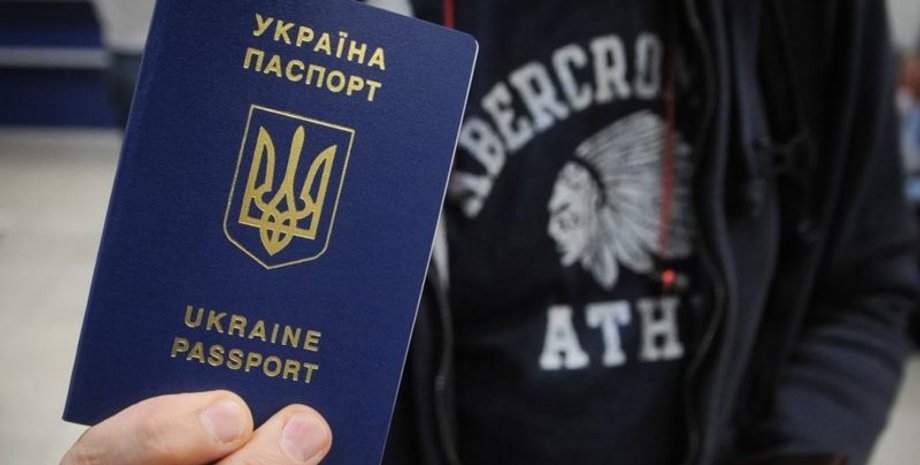 Молодий чоловік демонструє закордонний паспорт задля виїзду з України