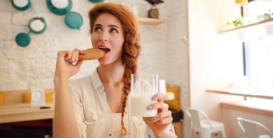 Девушка ест круассан и пьет молоко