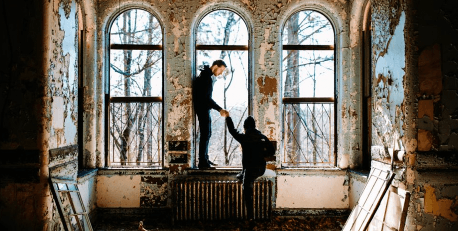 Міські дослідники в покинутому будинку в Англії Двоє міських дослідників у порожньому будинку з облупленими стінами і високими вікнами