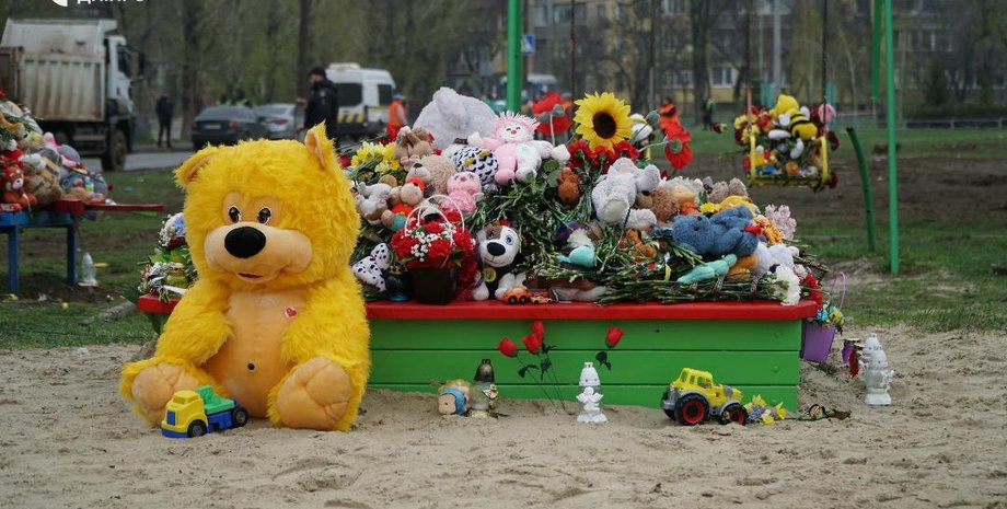 Люди несут цветы и игрушки на место удара