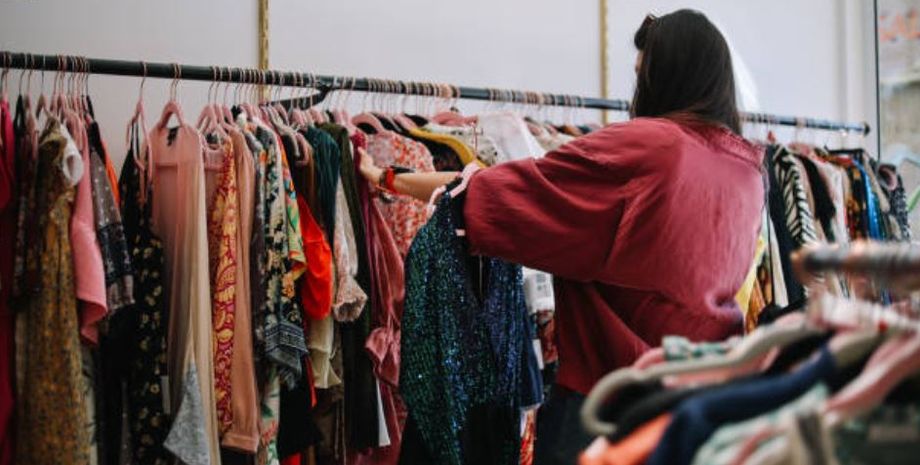 Жінка переглядає одяг на вішалках у благодійному магазині Соліхалла, де було виявлено сумку Aspinal of London за неймовірно низькою ціною