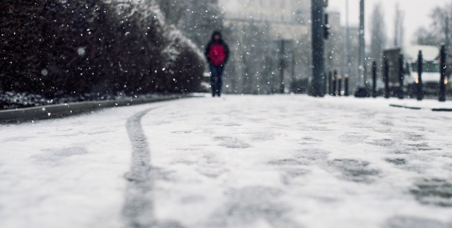 людина йде взимку по дорозі