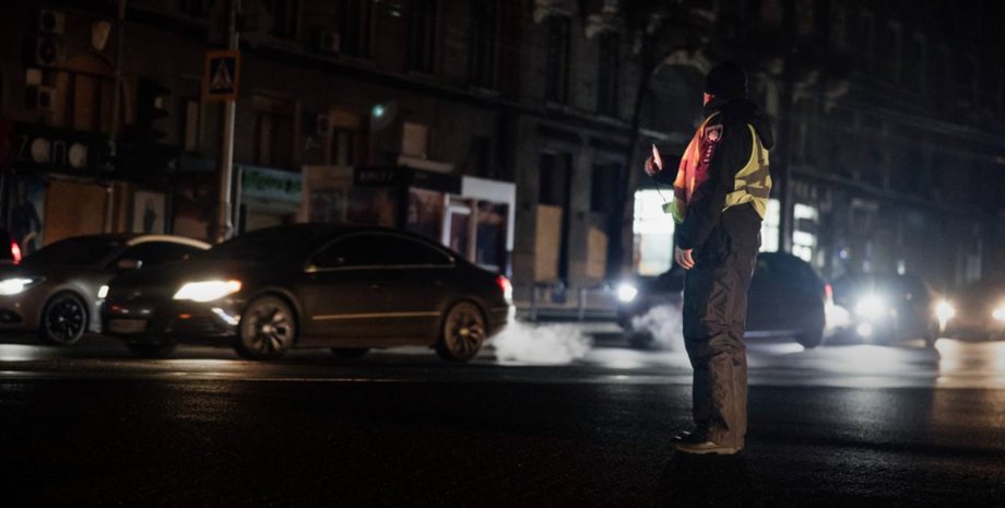 Харків під час перебоїв електроенергії ввечері 23 листопада Поліцейський регулює рух на темній вулиці Харкова під час перебоїв світла 23 листопада