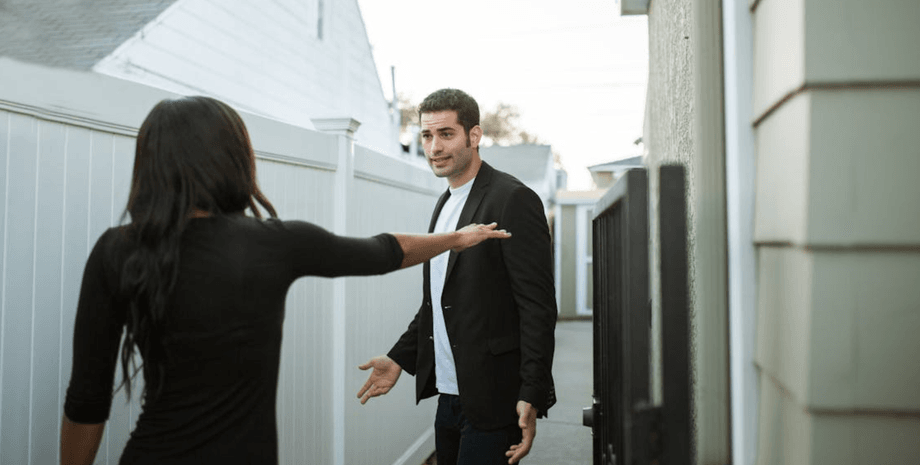 Мужчина и женщина у входа в частный дом после переезда обсуждают неожиданную ситуацию