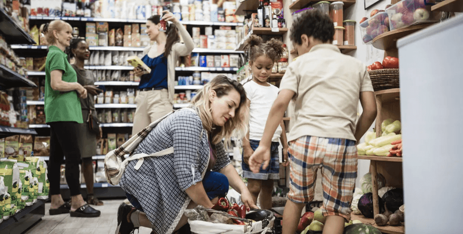 Молодая семья с детьми покупает овощи и продукты в супермаркете