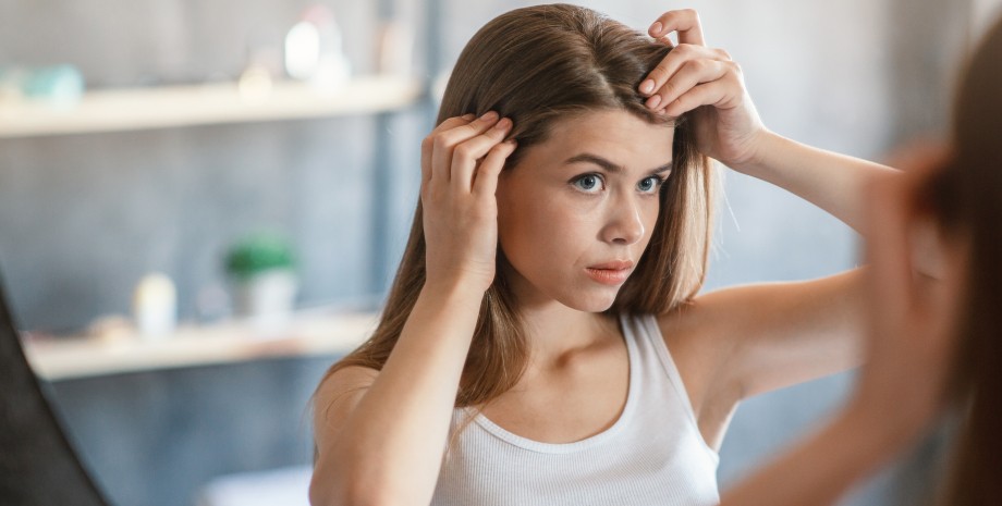 Як виявити дефіцит кальцію Дівчина дивиться в дзеркало