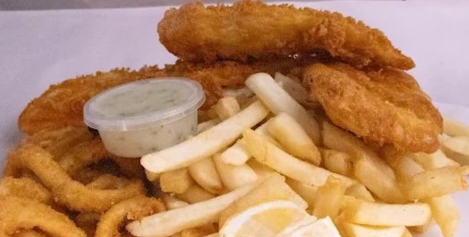 Смажена риба, картопля фрі, кальмари та соус тартар на тарілці в ресторані Перта