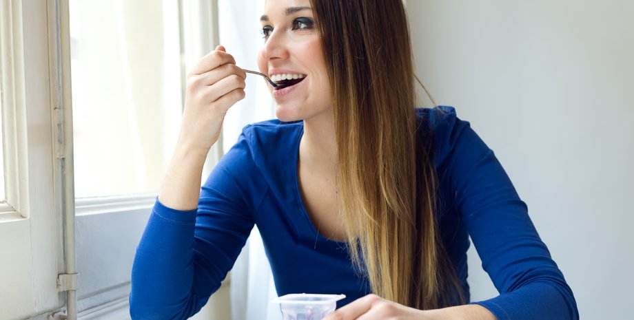 Девушка ест йогурт