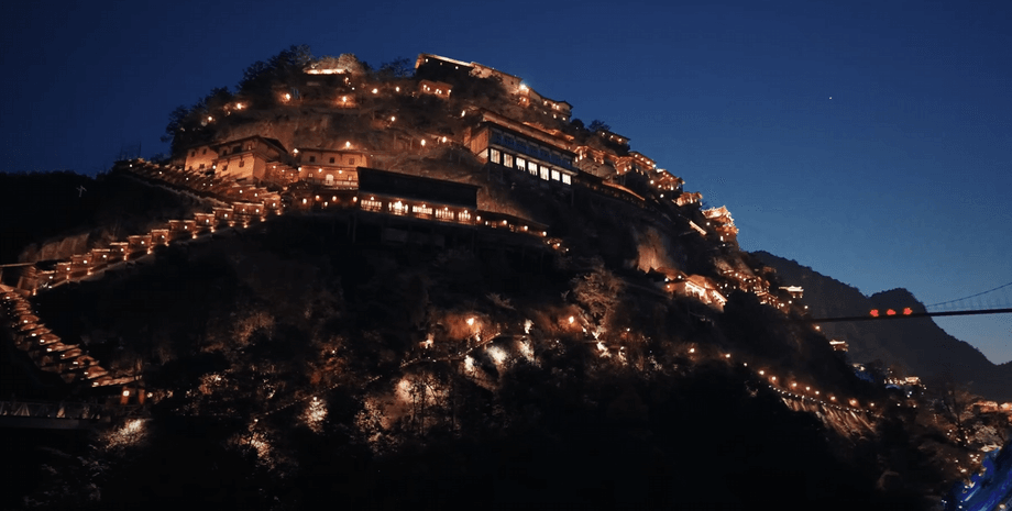 Ночные огни освещают старинные здания и лестницы на крутом склоне горы в долине Вансянь, Китай