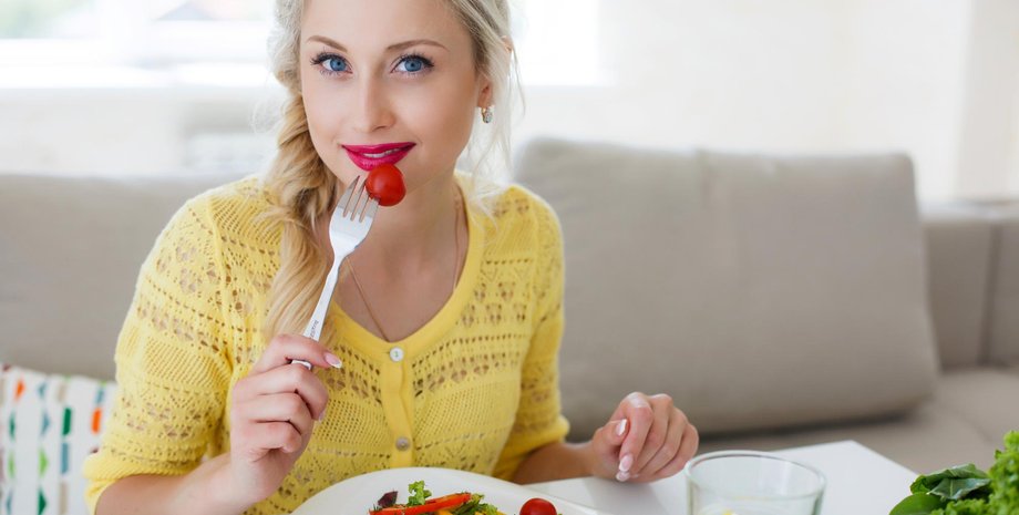 Девушка ест помидор