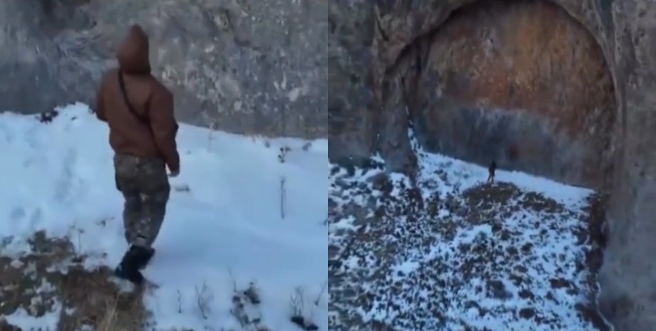 Два человека стоят у скального образования в горах Джунгарского Алатау в Казахстане, прозванного "дверным проемом"