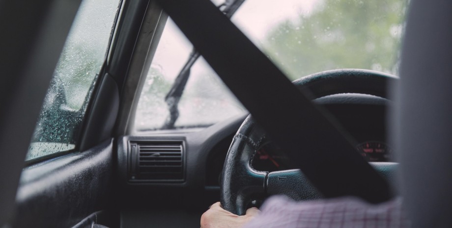 Водій Водій їде за кермом машини у дощ