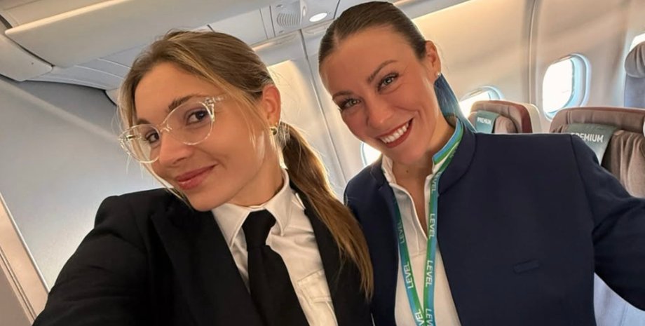 Бортпроводницы в салоне самолета улыбаются пассажирам и советуют сохранять спокойствие во время праздничных перелетов