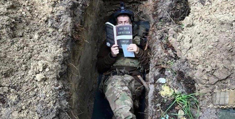 солдат в окопі читає книгу