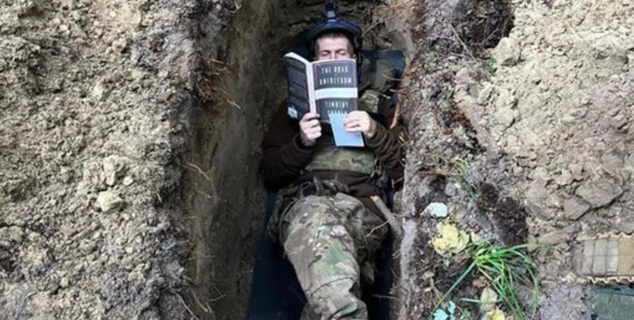 солдат в окопе читает книгу