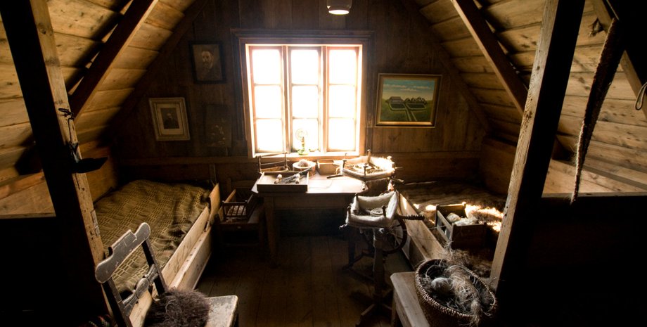 Інтер'єр старого горища з дерев'яними стінами, вікнами та старовинними меблями