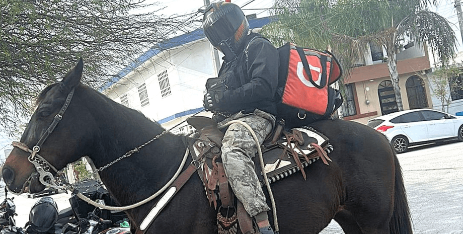 Кур'єр із рюкзаком служби доставки їде верхи на коні міською дорогою поруч з автомобілями в Мексиці