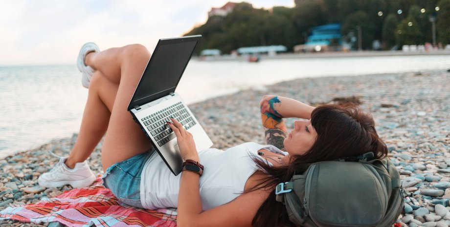 Работа в отпуске, девушка с ноутбуком на пляже