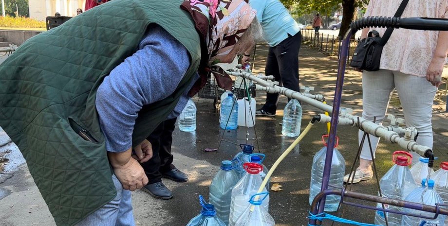 Бабушка набирает воду в бутылки