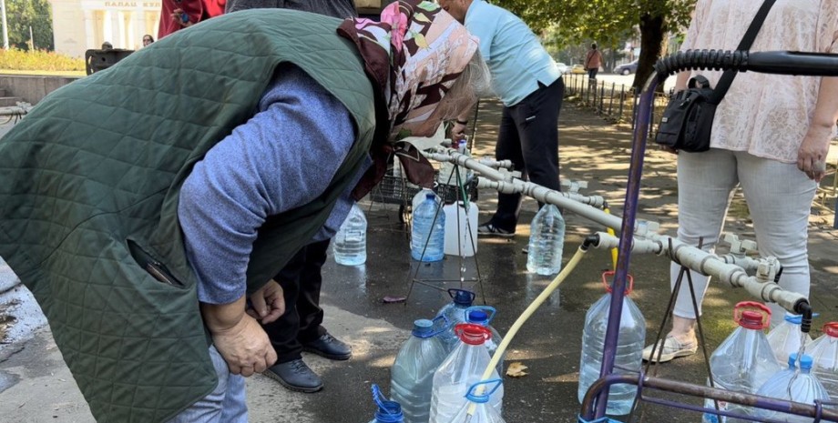 Бабушка набирает воду в бутылки