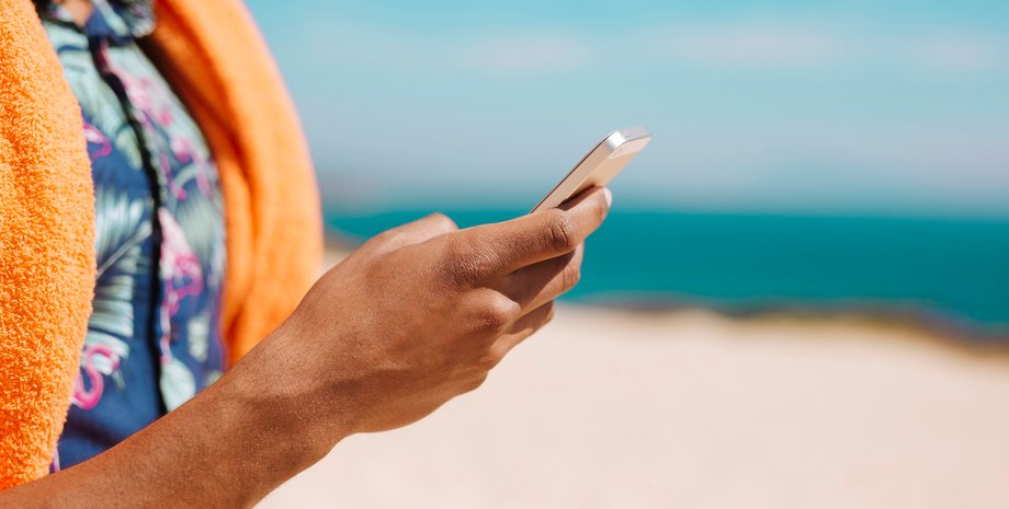 Чоловік використовує смартфон на пляжі