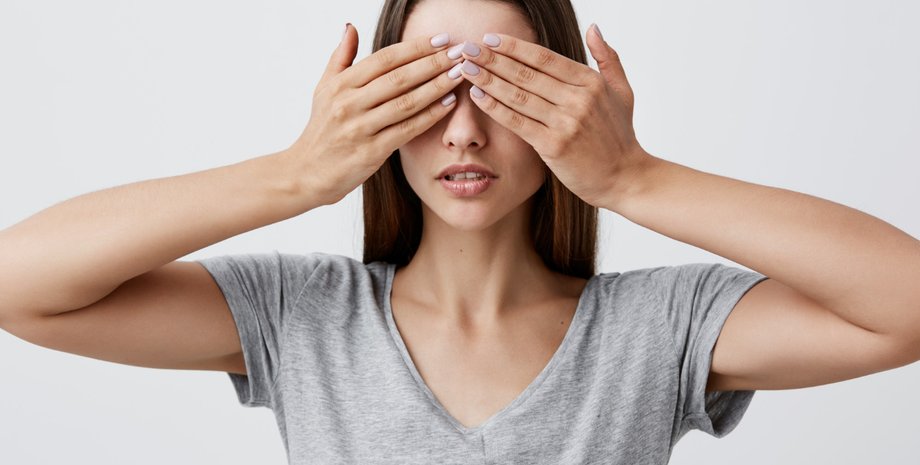 Девушка закрывает лицо руками
