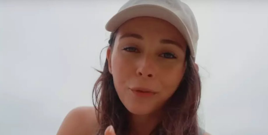 Молода жінка в білій кепці записує відео, ділячись історією про роботу на круїзному судні