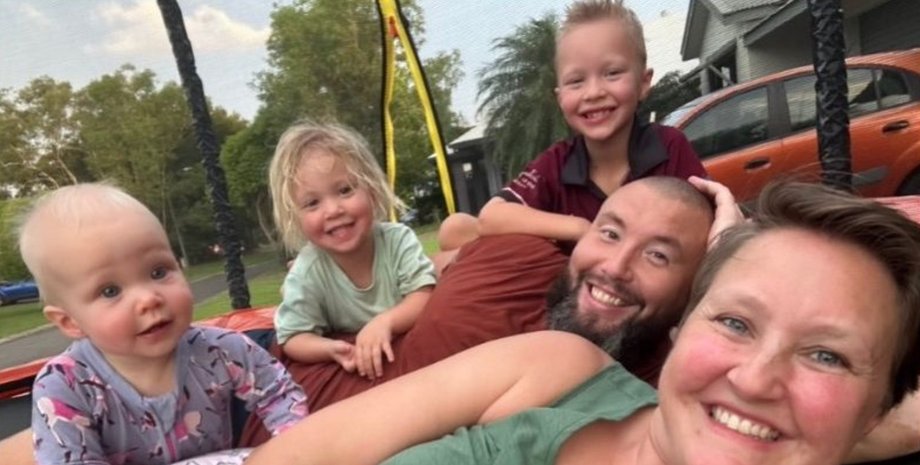 Улыбающаяся семья с тремя маленькими детьми отдыхает на улице перед домом, Австралия