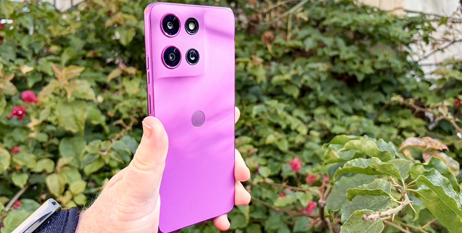 Пользователь держит смартфон Moto G 2026 в руке на фоне кустов