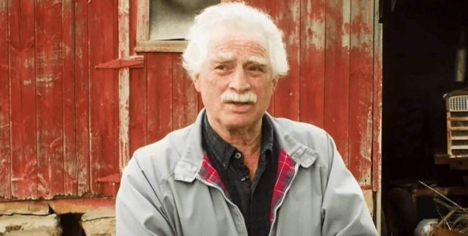 Філіп Гашейдер стоїть біля старої червоної комори, розповідаючи про пережитий досвід клінічної смерті