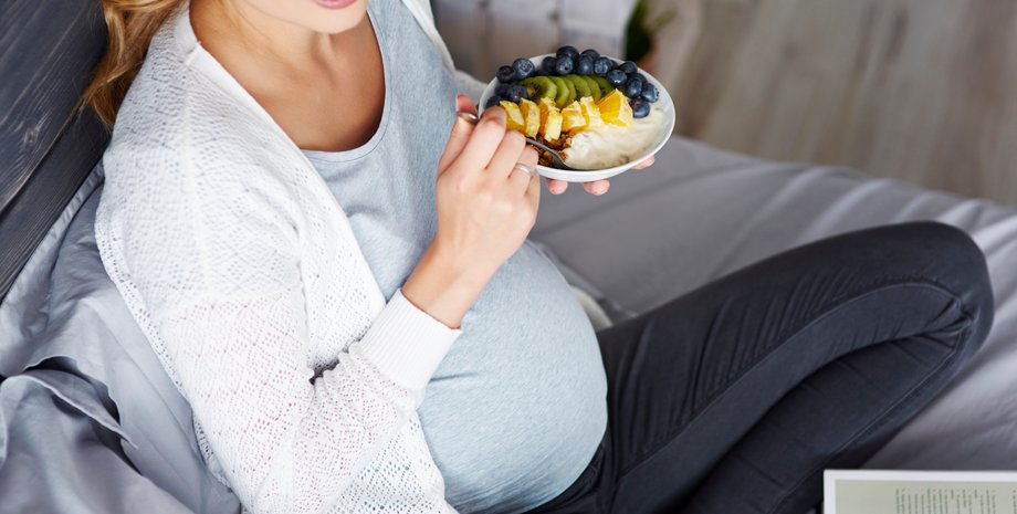 Вагітна жінка їсть фрукти