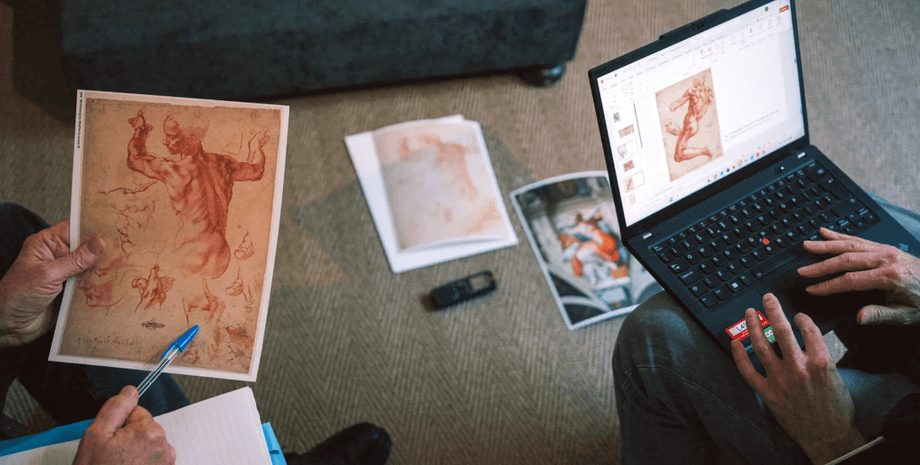 Двое специалистов рассматривают подготовительный рисунок Микеланджело, сравнивая распечатки и изображения на ноутбуке