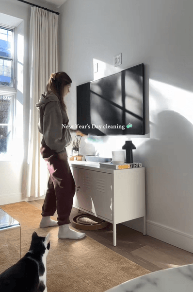 Жінка прибирає вітальню в чужому будинку під час нагляду за житлом, економлячи на оренді