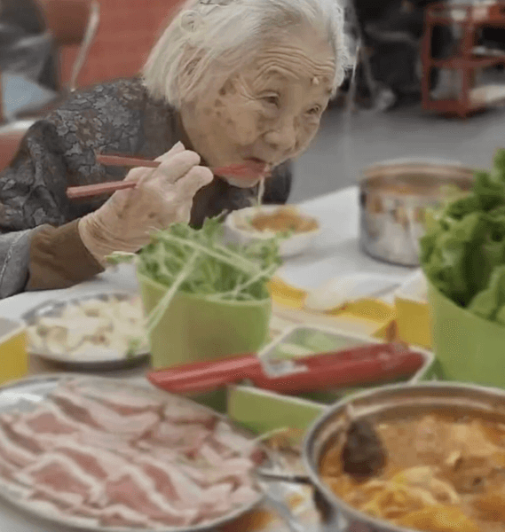 101-летняя женщина ест за столом во время путешествия с семьей, продолжая вести активный образ жизни