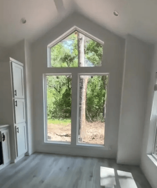 Світла кімната з високими вікнами та мінімалістичним інтер'єром