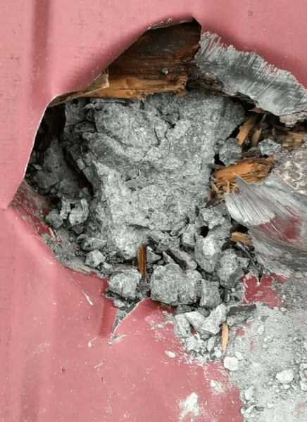 Крупный план дыры в металлической крыше и рассыпавшиеся фрагменты упавшего метеорита