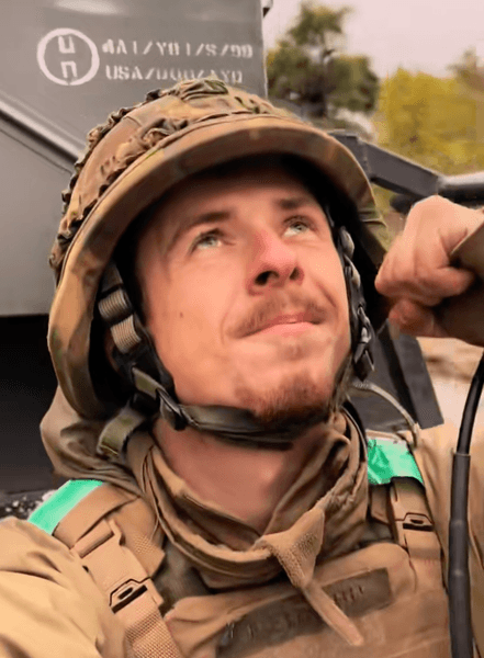 Український військовослужбовець у шоломі та спорядженні знімає відео під час служби