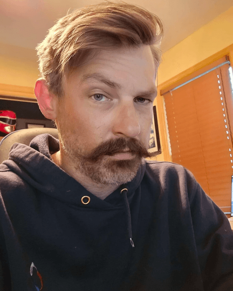 Мужчина с короткой щетиной и ухоженными усами после бритья