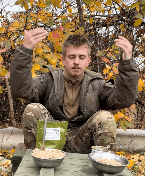 Військовий дегустує армійський сухпайок на фронті, показуючи раціон і страви з пайка різних армій